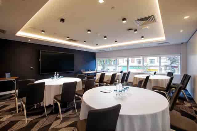 Modern boardroom at Royal National Hotel with round tables for workshops and strategic meetings.