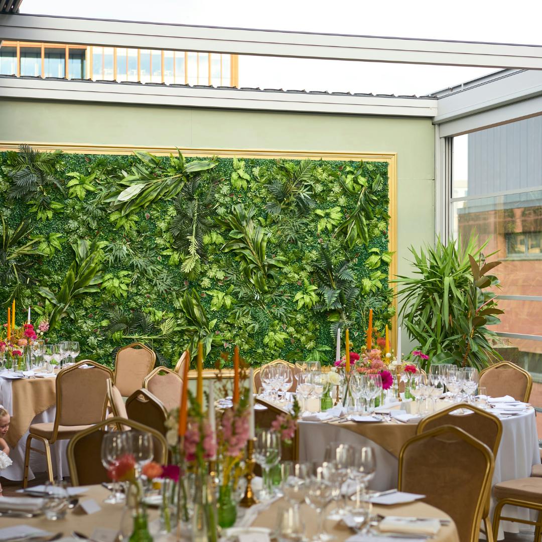 Elegant event space in Manchester Hall with lush green wall and floral centerpieces.