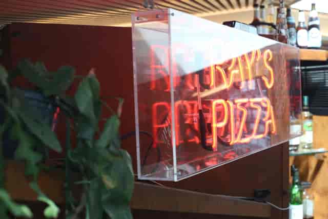 Vibrant neon pizza sign at Aldgate Tap, ideal for casual gatherings and networking events.
