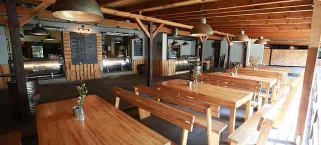 Rustic venue with long wooden tables for casual gatherings and workshops.