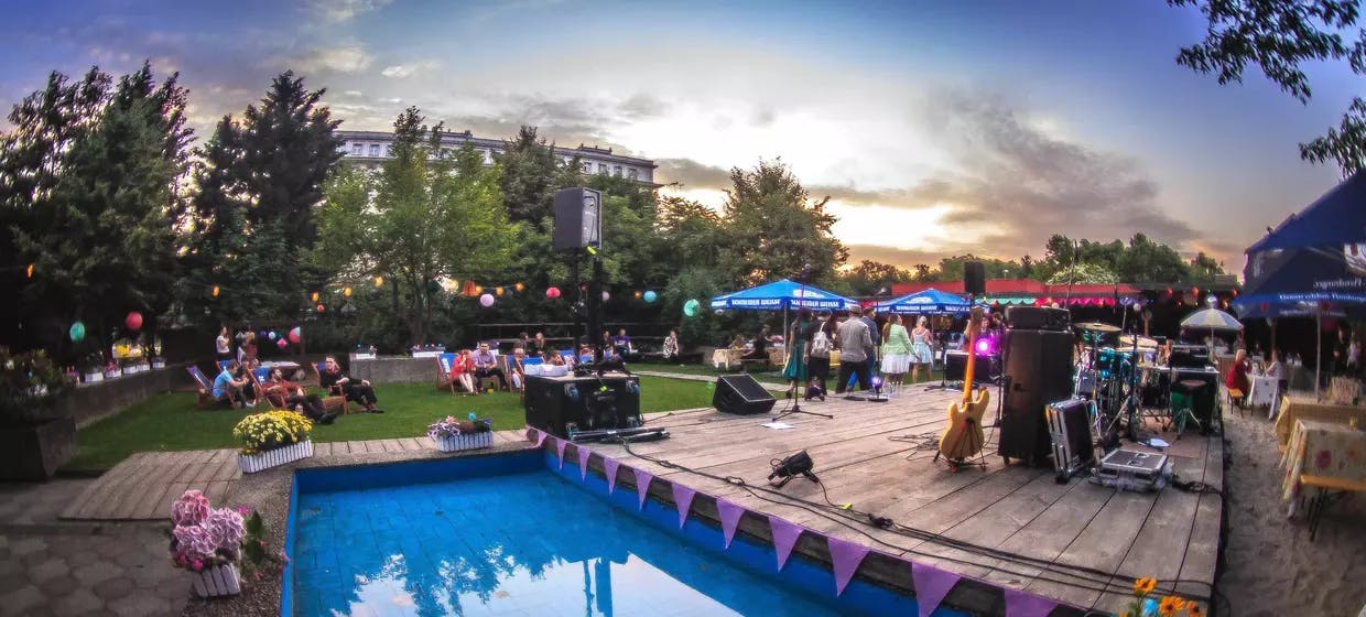 Vibrant outdoor restaurant event space with stage, ideal for summer soirées and corporate retreats.