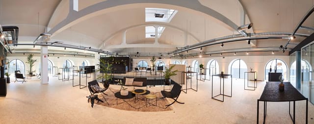 Modern event venue with high ceilings, perfect for networking and workshops.