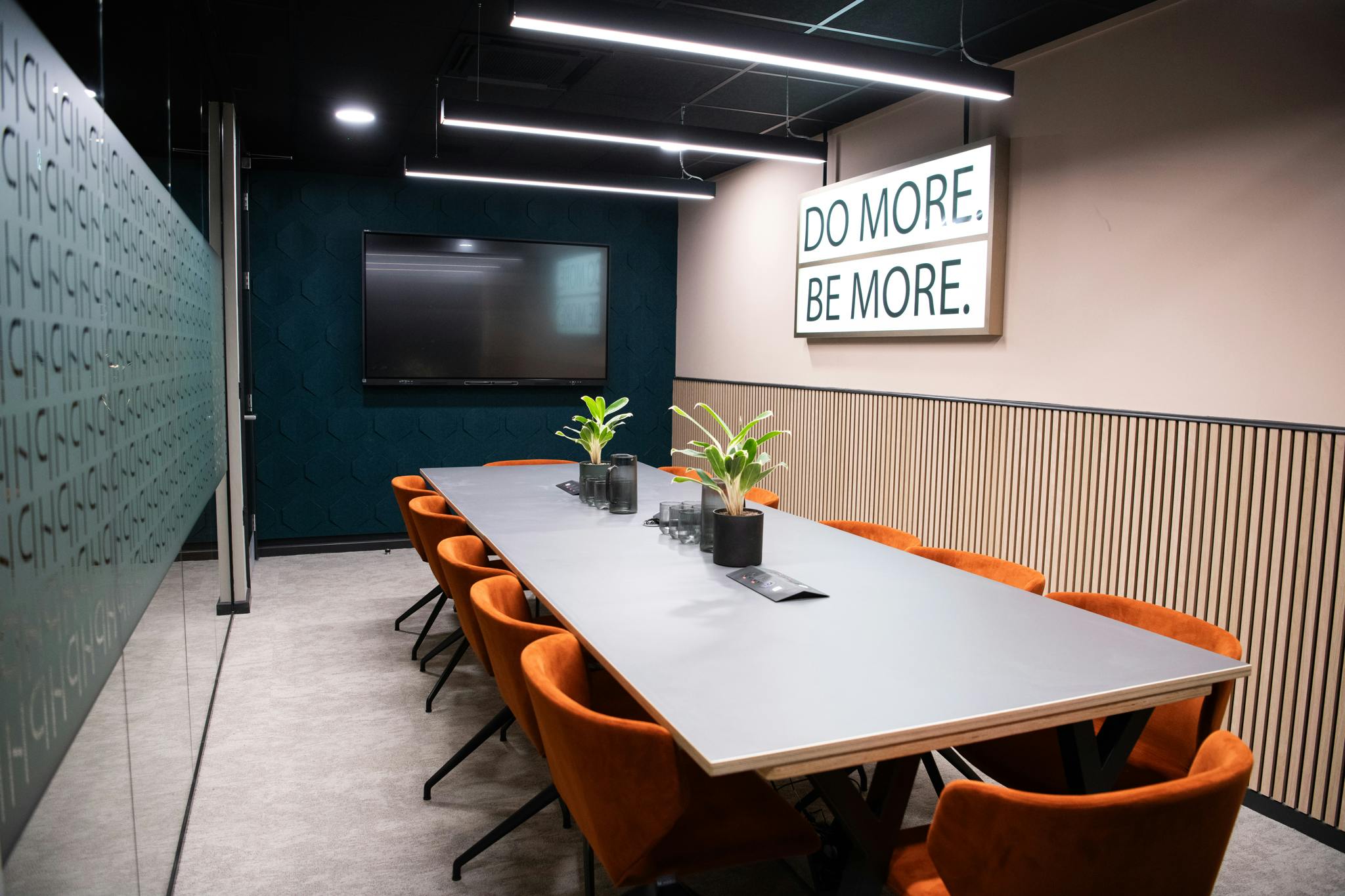 Modern meeting room in Wizu Workspace with sleek table and motivational wall art.