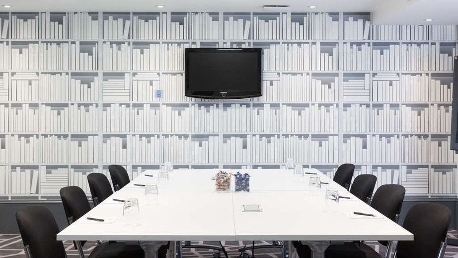 Modern meeting room at Village Hotel Bury with sleek table, ideal for conferences and brainstorming.