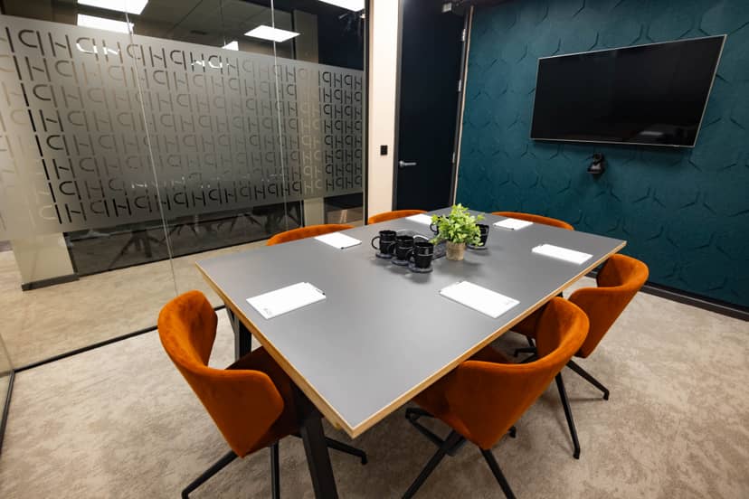 Modern conference room with gray table and orange chairs at Wizu Workspace.