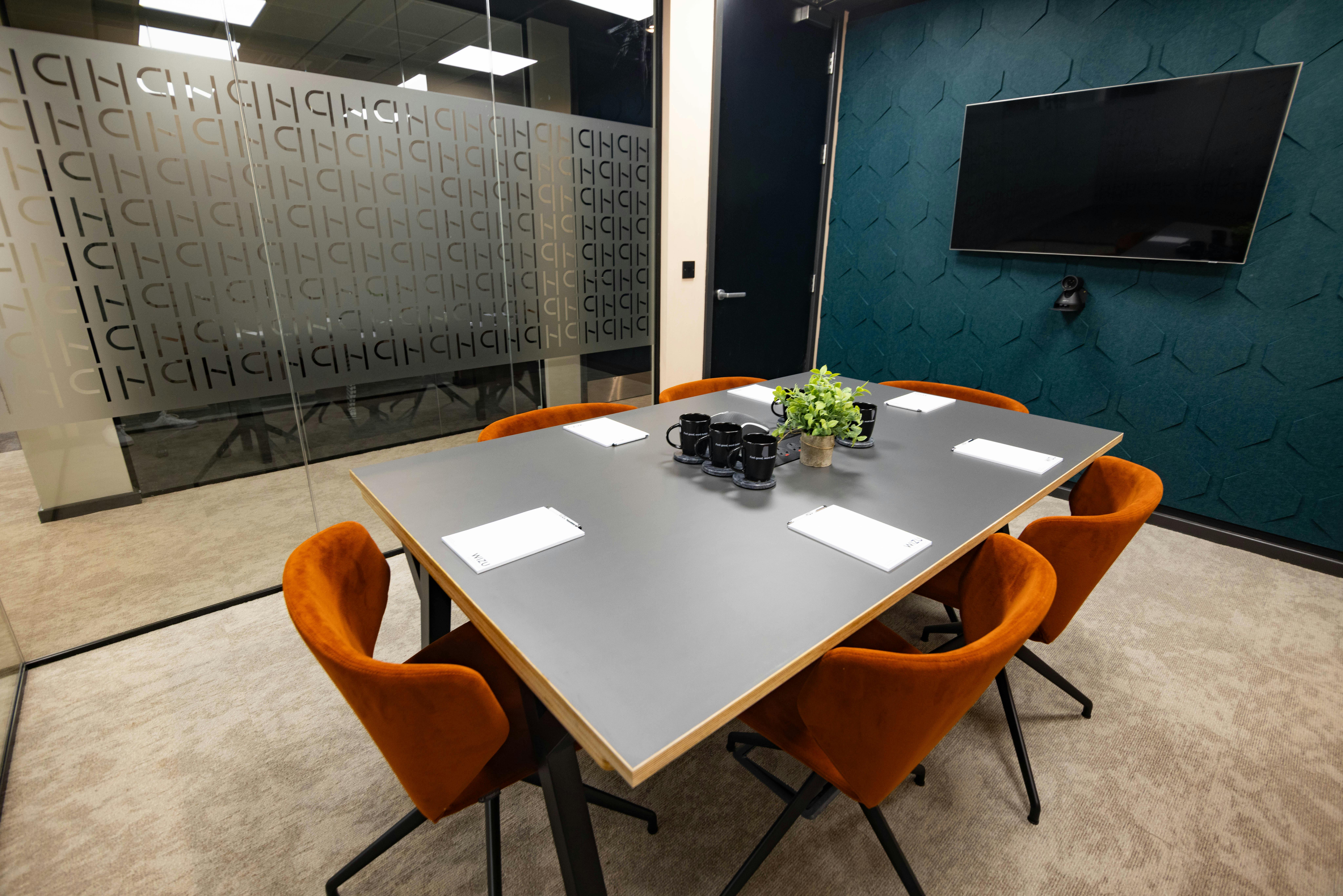 Modern conference room with gray table and orange chairs for professional meetings.