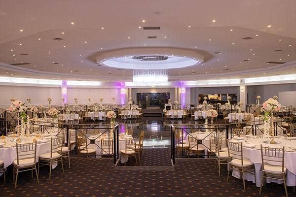 Elegant wedding venue with floral centerpieces and luxurious chandelier at Ultima Function Centre.
