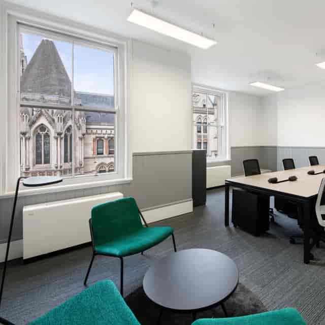 Modern meeting room with large table and green chair, perfect for collaboration events.