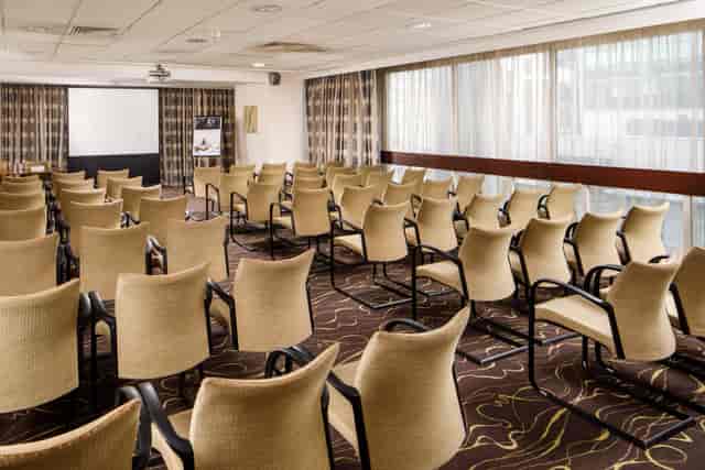 Meeting room at Mercure Manchester Piccadilly, featuring beige chairs for corporate events.