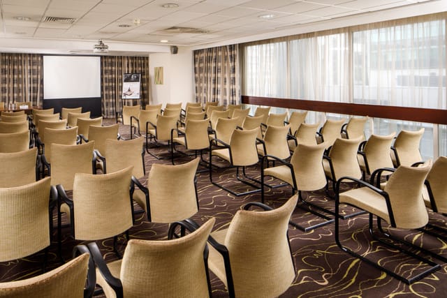 Meeting room at Mercure Manchester Piccadilly, featuring beige chairs for corporate events.