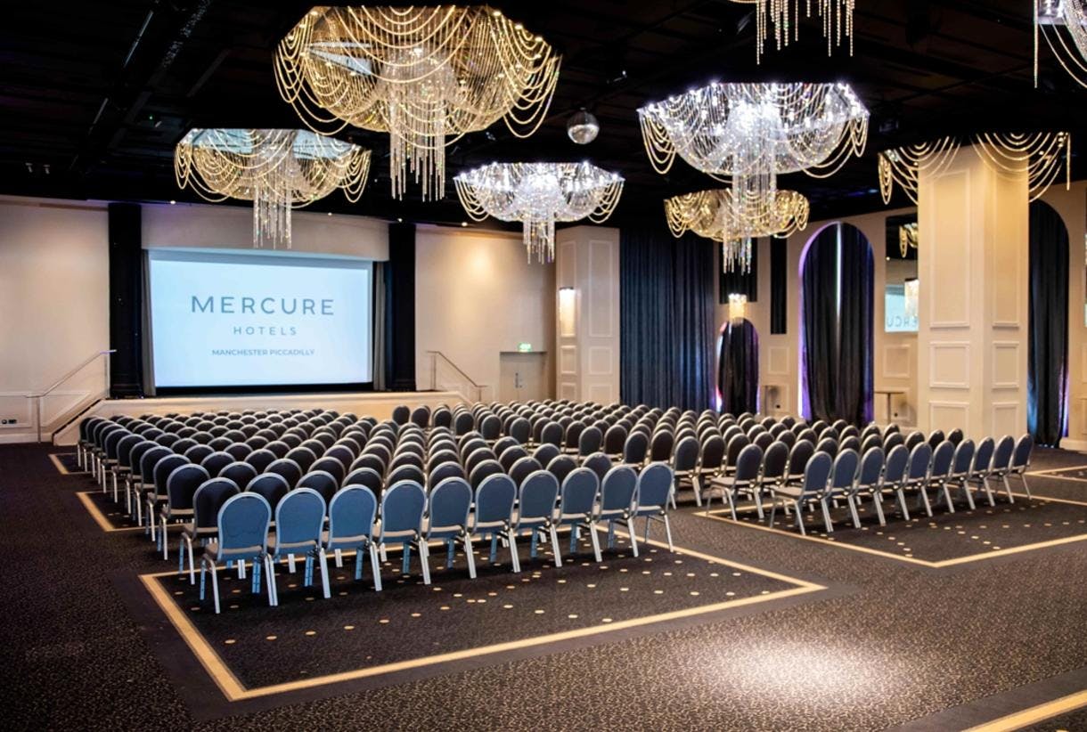 Event space with blue chairs and chandeliers at Mercure Manchester Piccadilly Hotel.