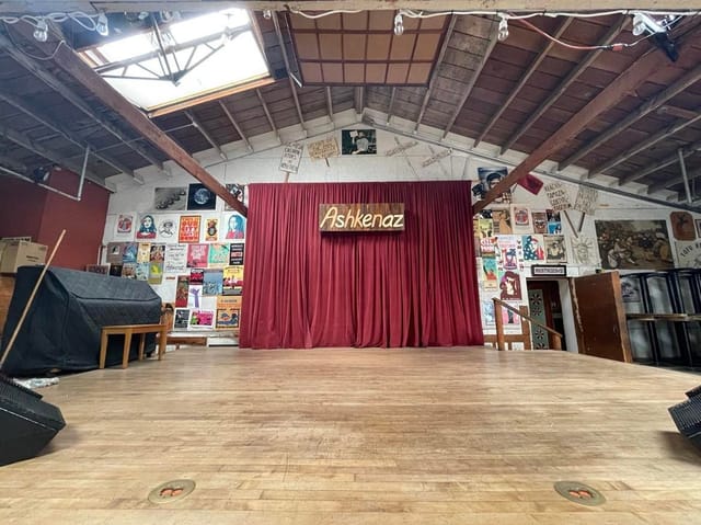Front Dance Hall at Ashkenaz Center, red curtain stage, ideal for performances and events.