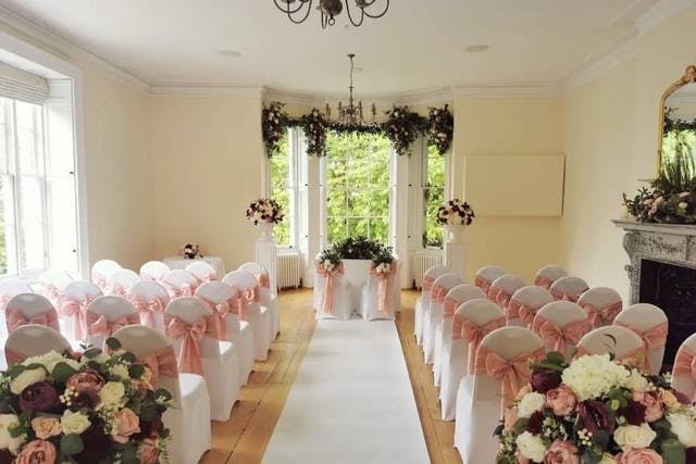 Elegant wedding ceremony setup in The Russell Suite with white chairs and pink sashes.