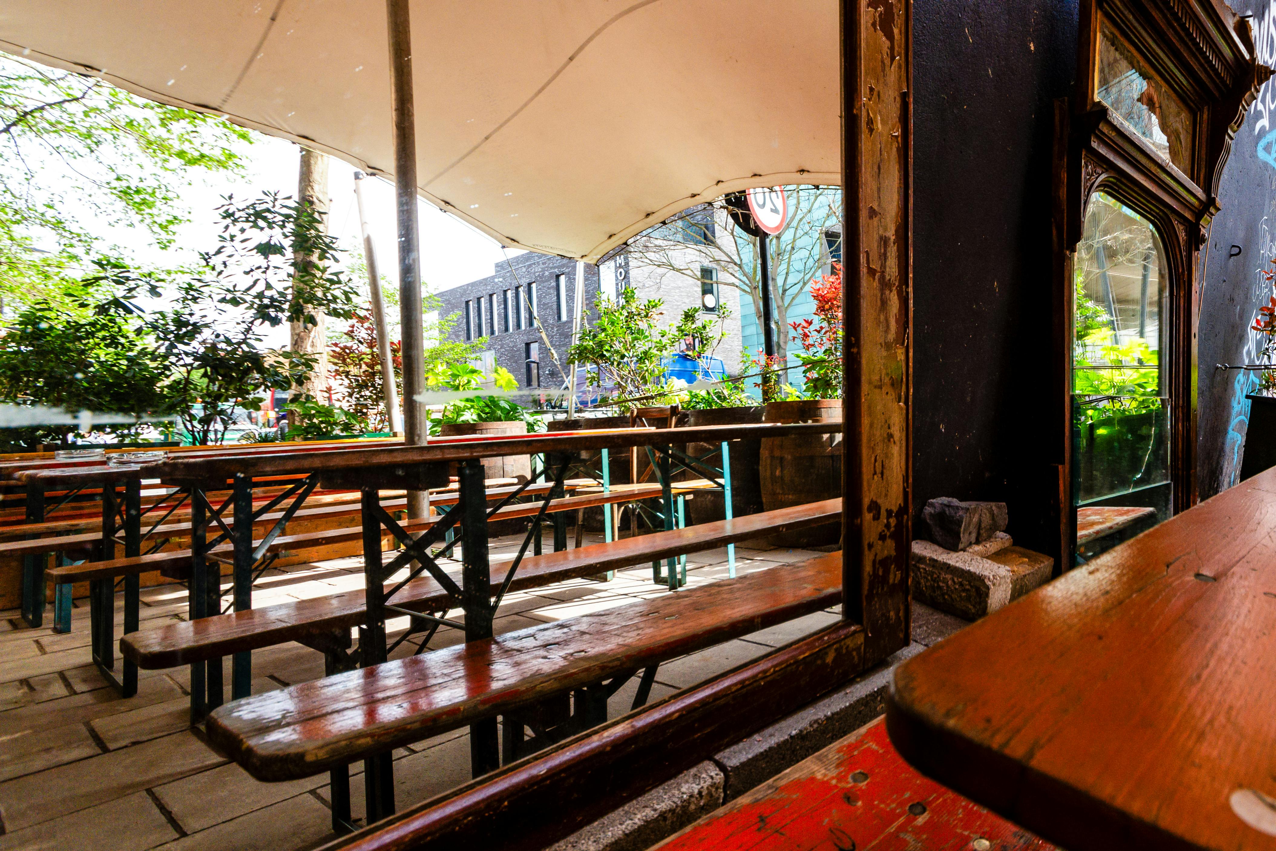 Outdoor event space at The Greyhound Peckham with rustic benches and summer ambiance.