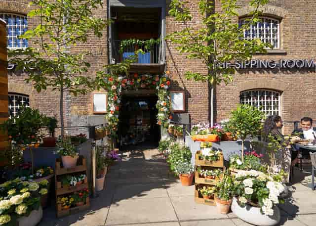 Charming outdoor venue entrance with vibrant flowers, perfect for weddings and garden parties.