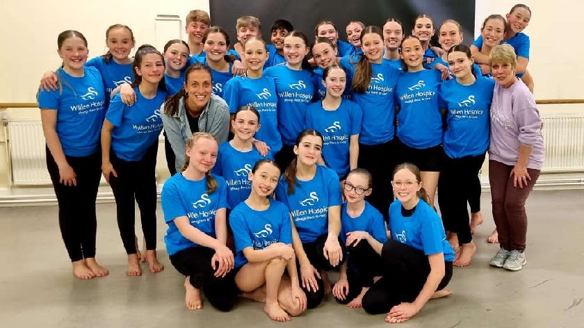 Vibrant dancers in blue shirts at Myra Tiffin Performing Arts School for team-building events.