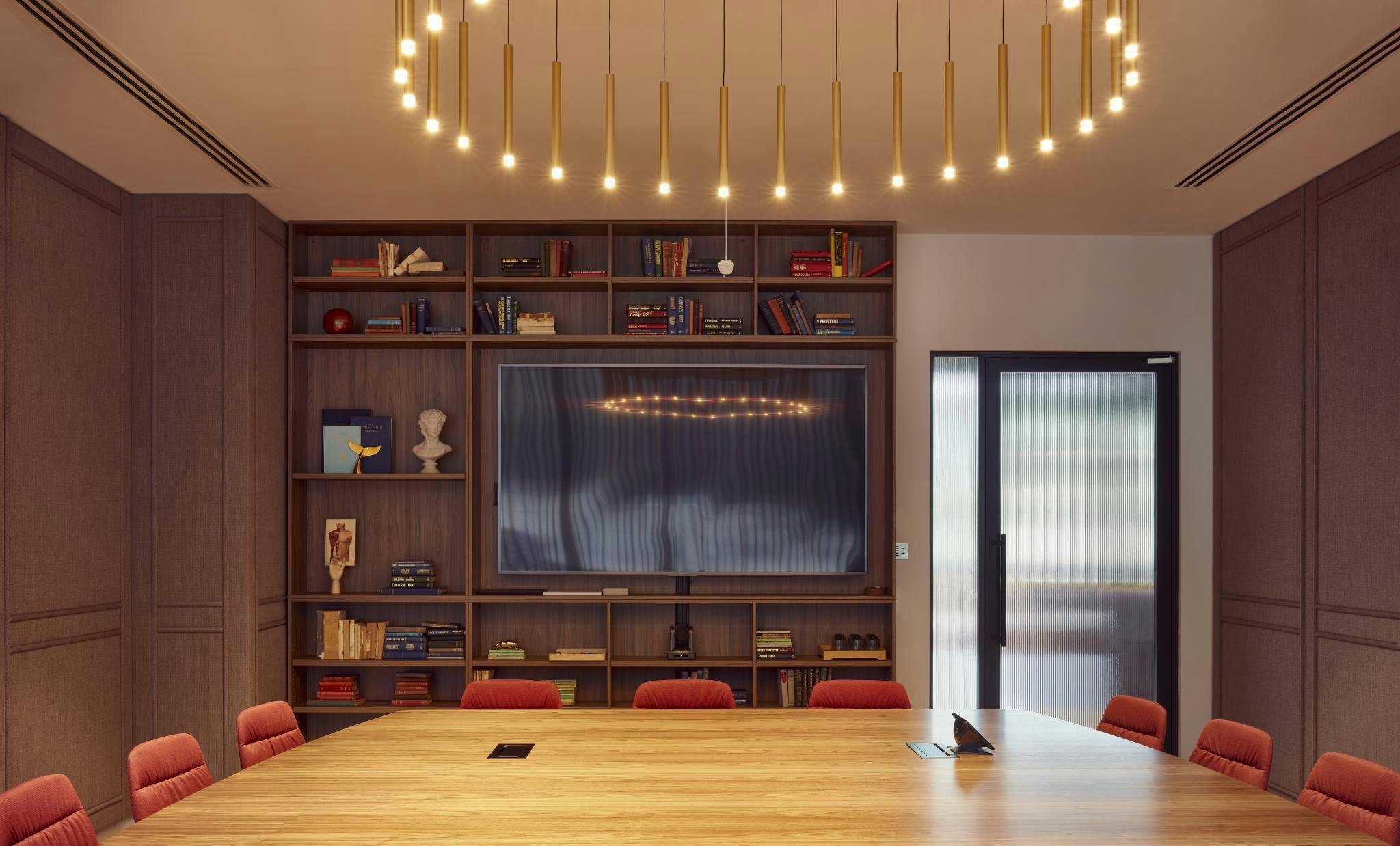 Modern conference room with wooden table and red chairs at Storey Club Paddington Central.