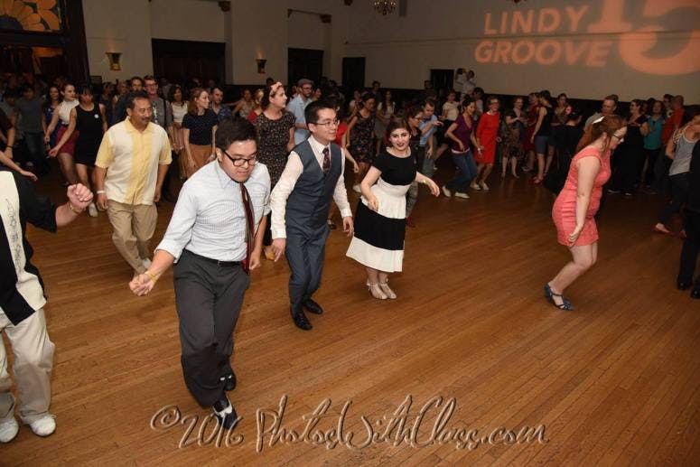 Lively swing dance event in a spacious ballroom with warm lighting and energetic participants.