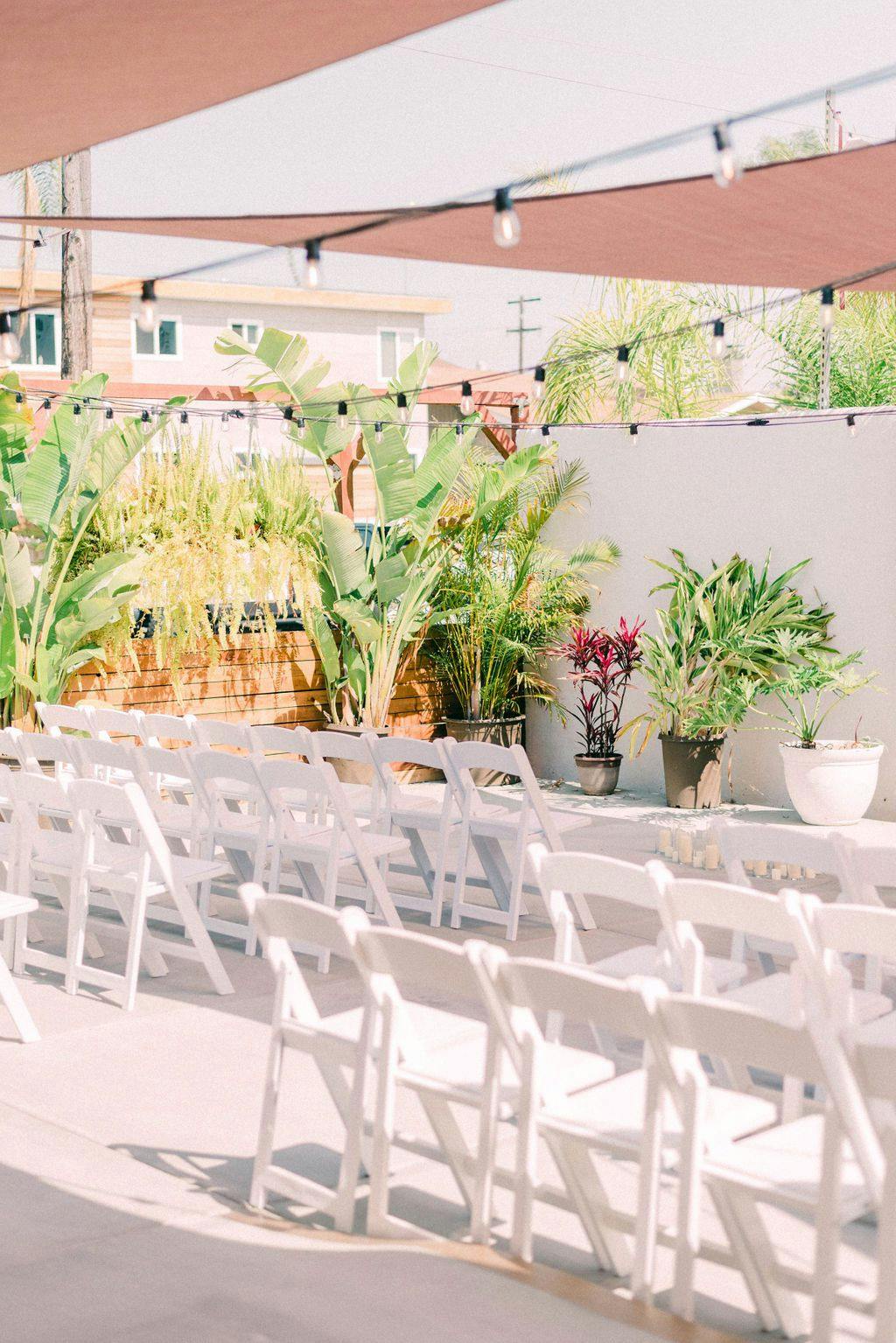 Outdoor event space with white chairs and string lights at FruitCraft Distillery.