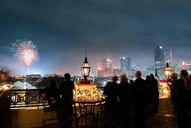 Rooftop event with skyline view, string lights, and fireworks for celebrations.