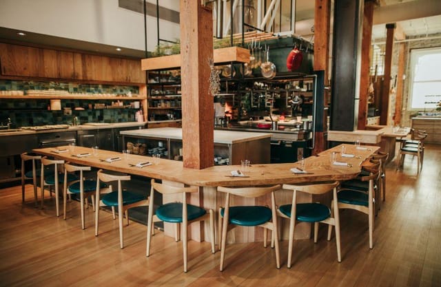 Modern dining space with wooden table for private dinners and culinary events.