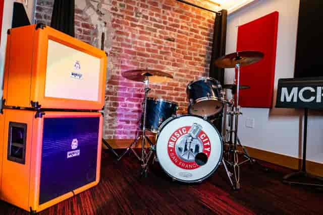 Vibrant music studio with orange amplifier and drum kit for live performances and events.
