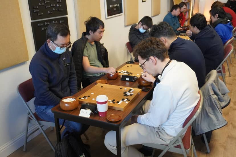 San Francisco Go Club members playing a strategic board game with masks for safety.