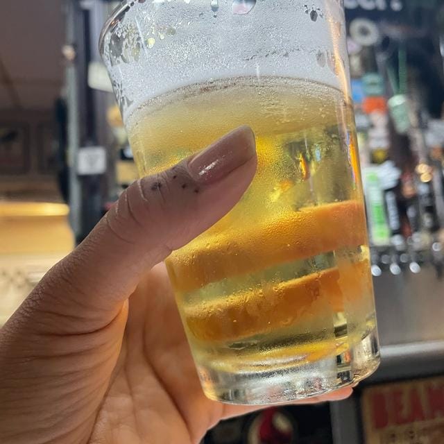 Hand holding a glass of beer at Mission Pizza & Pub for event planning and networking.
