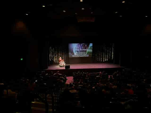 Mission Santa Clara event with speaker on stage in engaging theater setting.