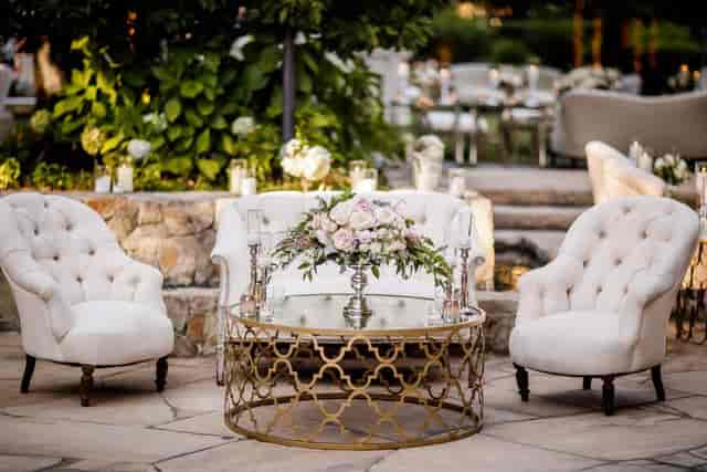 Elegant outdoor seating area with tufted chairs for weddings and upscale receptions.