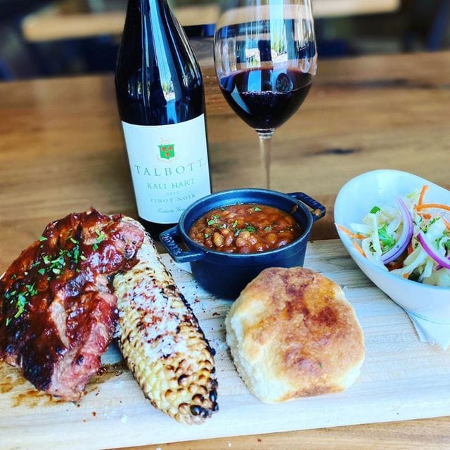Spacious Bar plate with barbecue ribs, cornbread, and red wine for events and catering.