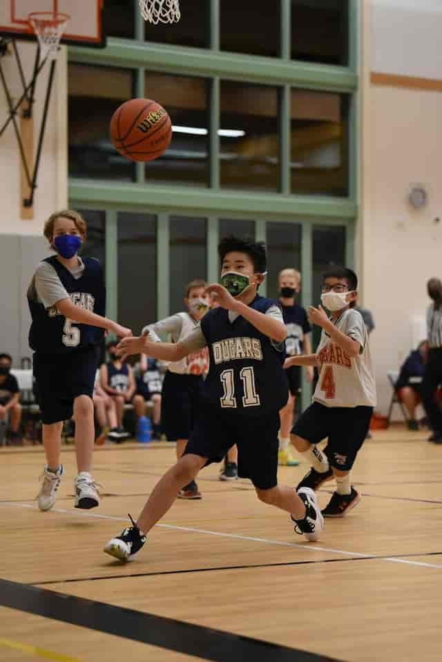 Youth basketball game at Fisher Event Center, showcasing teamwork and safety protocols.
