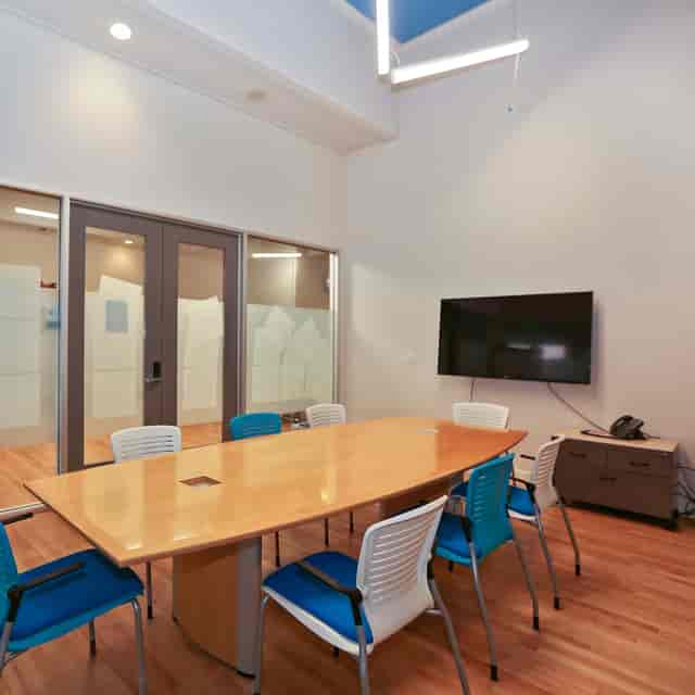 Modern meeting room with wooden table, colorful chairs for corporate events and brainstorming.