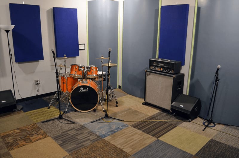 Band practice studio with drum set and acoustic panels for music events and workshops.
