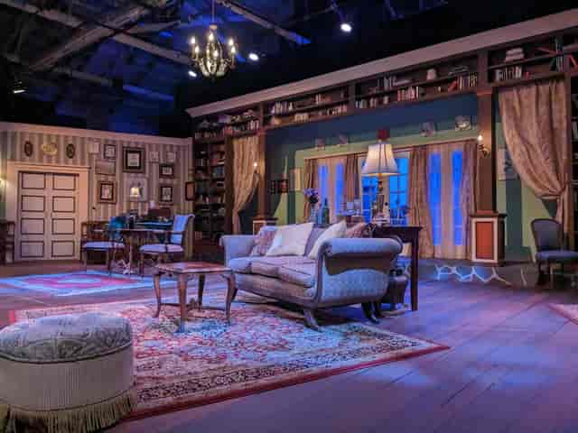 Outdoor patio stage set with elegant furnishings for intimate theatrical events.