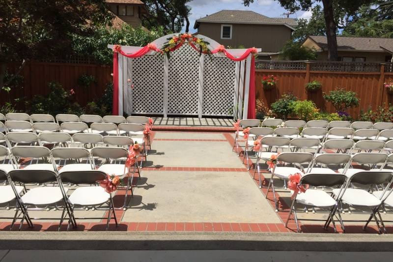 Beautiful garden ceremony space with decorated archway, perfect for weddings and events.