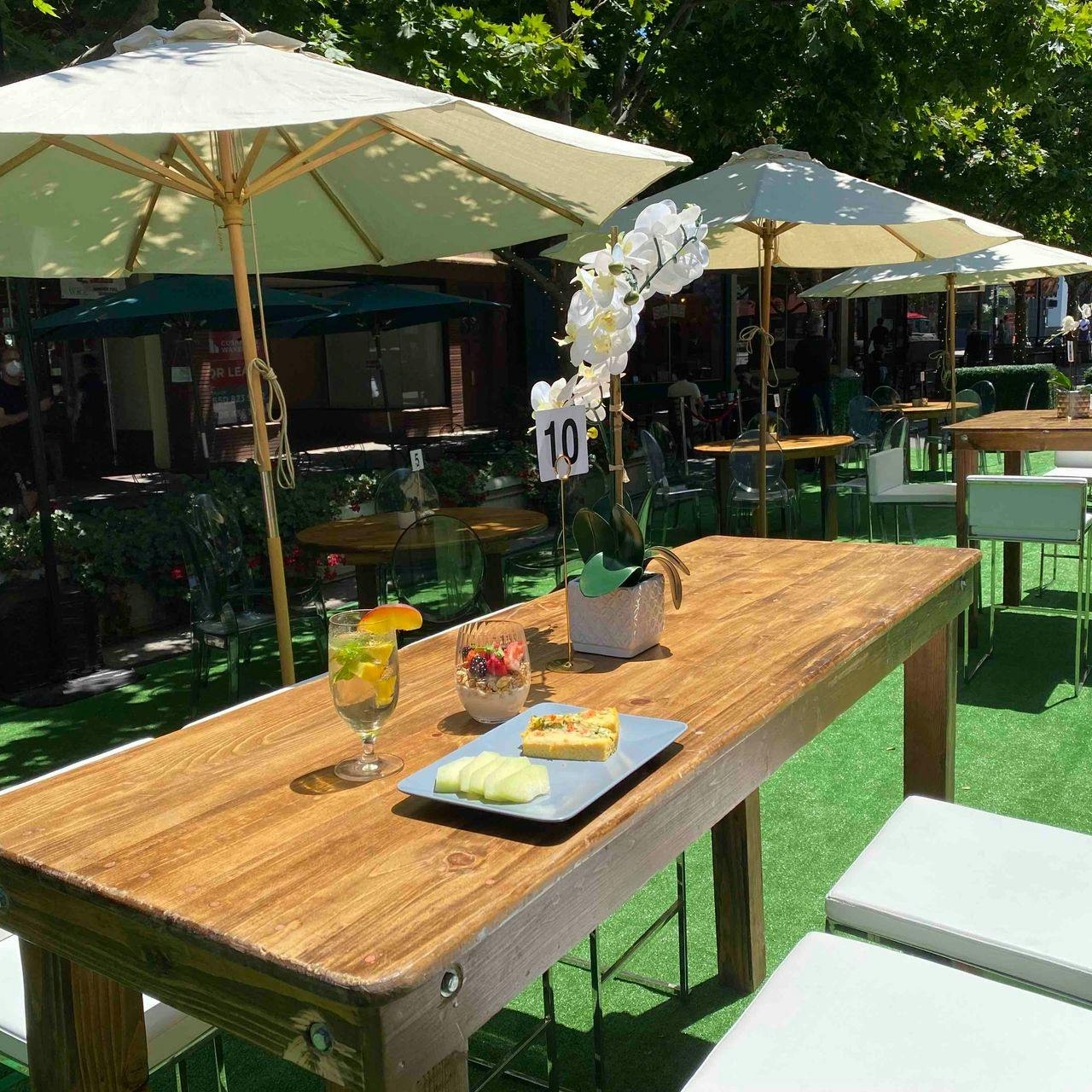 Outdoor event space at OPAL Social Club with a wooden dining table and floral centerpiece.