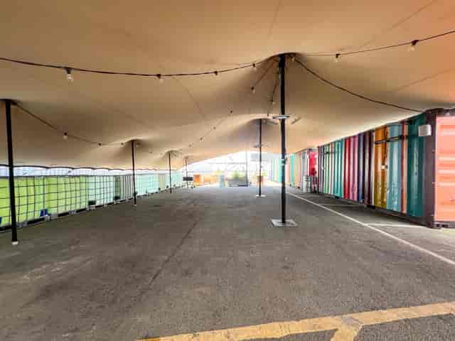 Versatile outdoor event space with tent and colorful containers for gatherings and exhibitions.