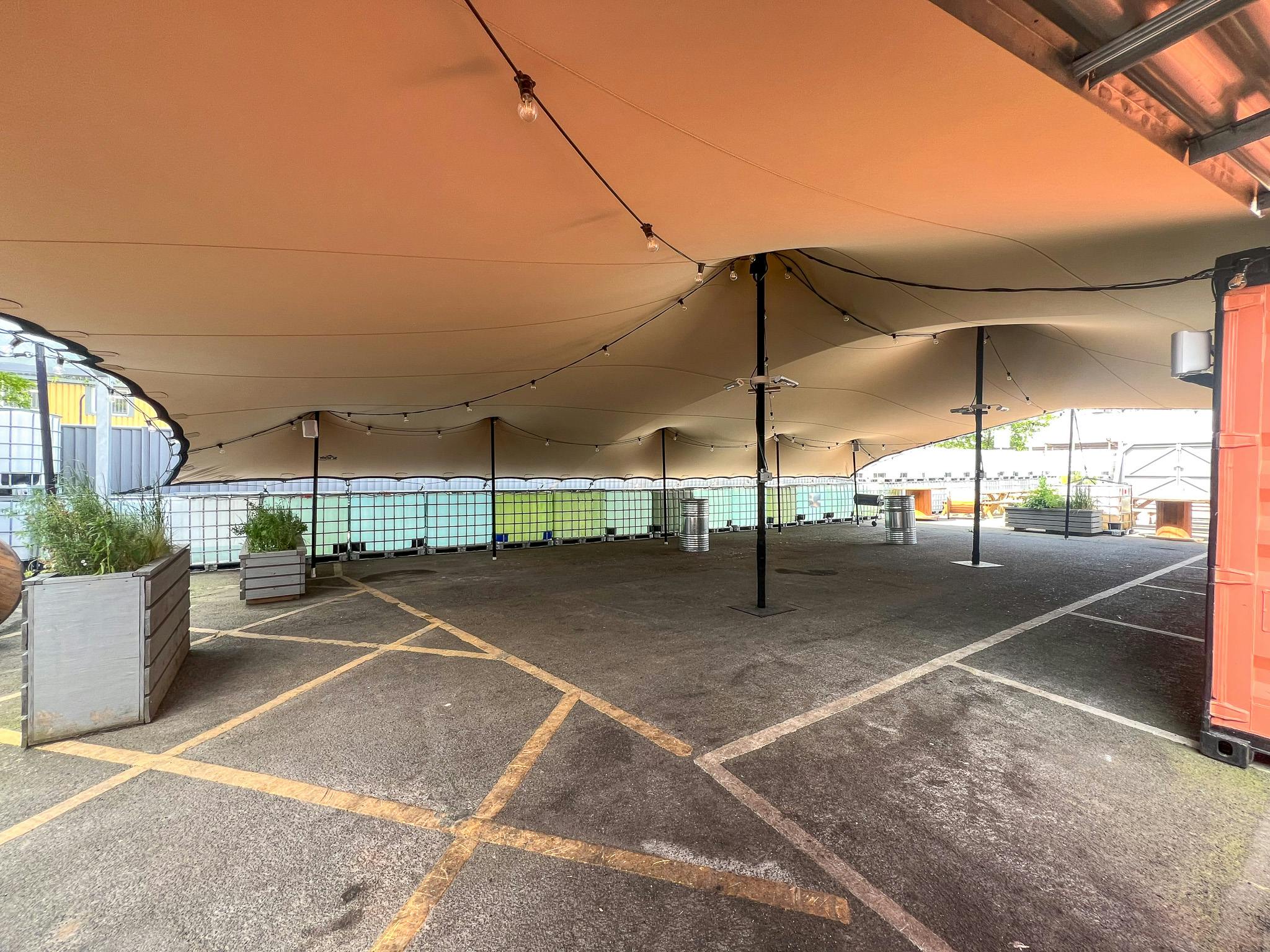 Versatile outdoor event space with canopy and string lights for gatherings and film events.