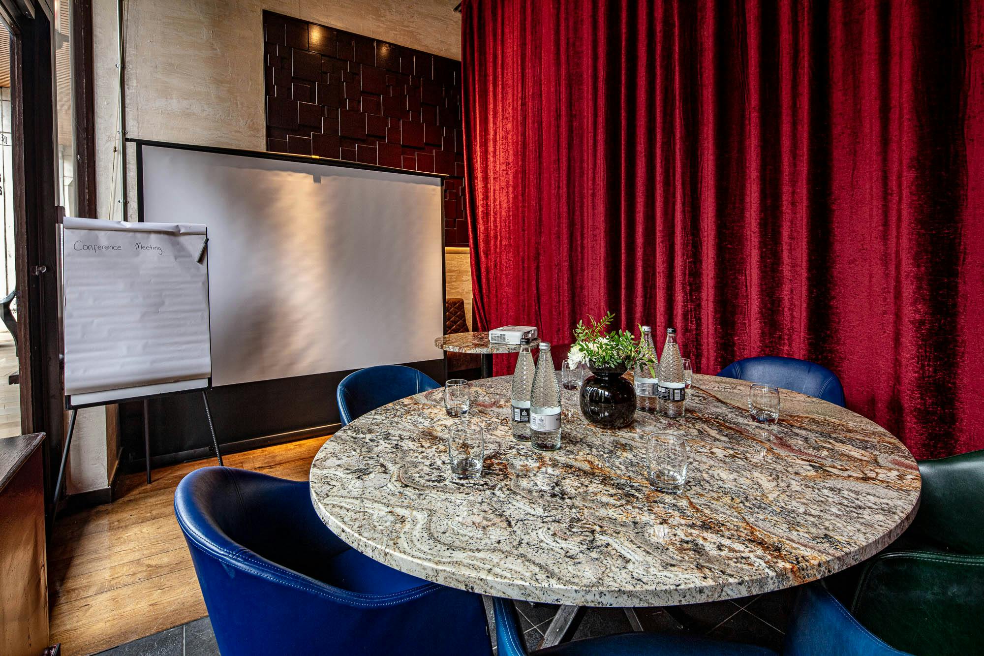 Regent Parlour meeting space with marble table, blue chairs, ideal for presentations.