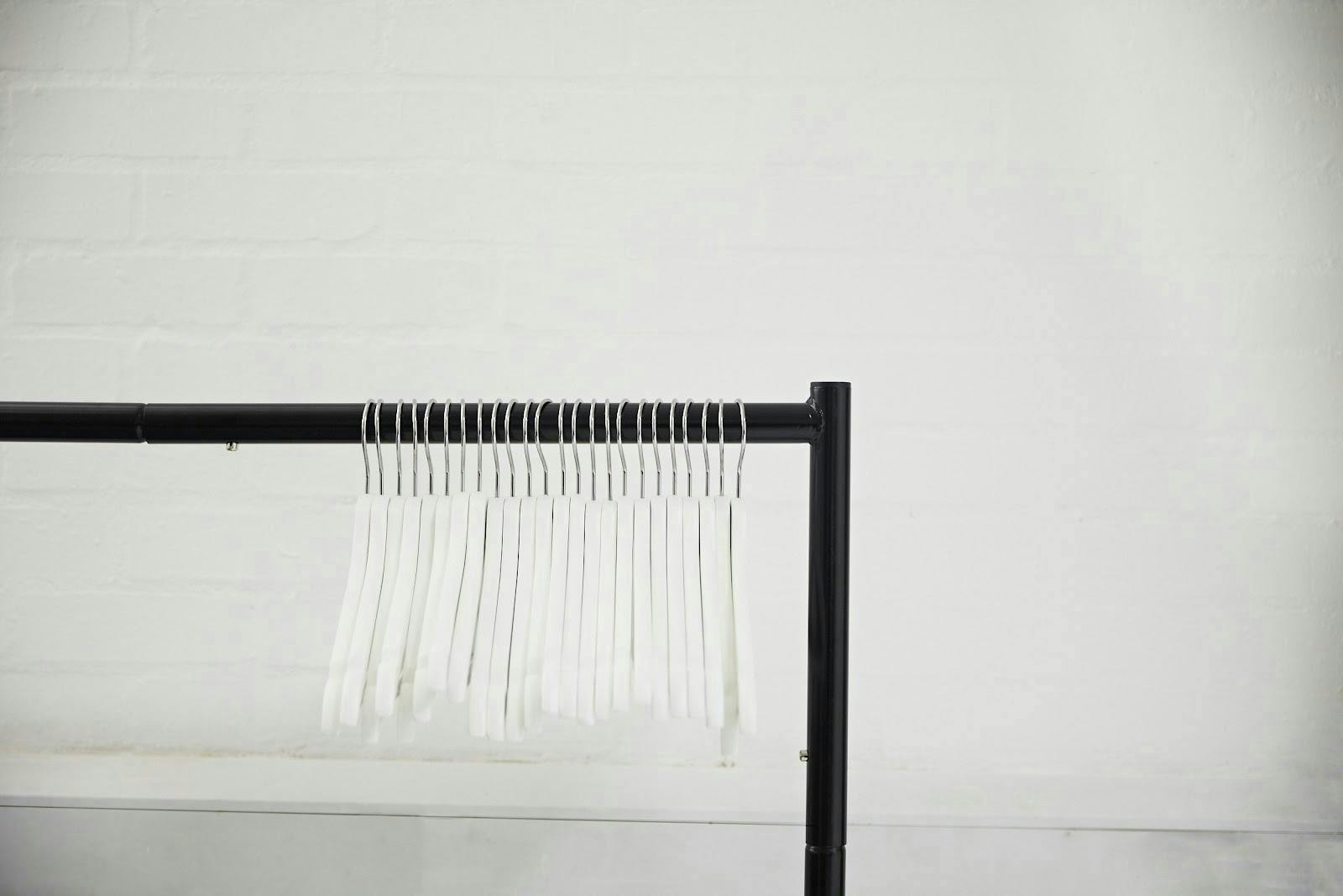 Minimalist clothing rack with white hangers for elegant fashion events and trade shows.