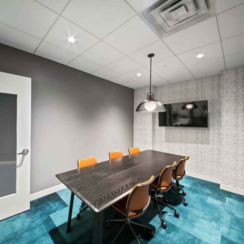 Modern NYC meeting room with sleek table, orange chairs for collaboration and brainstorming.