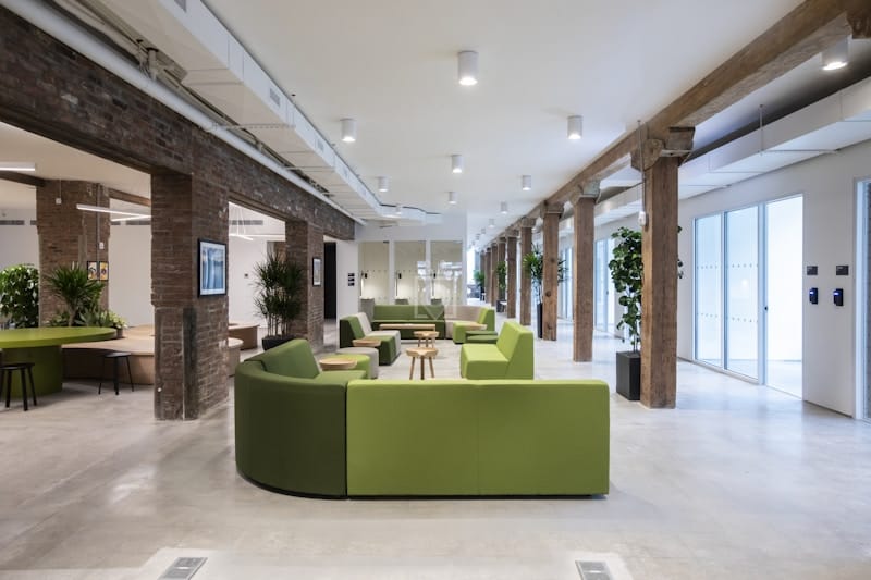 Modern private offices with vibrant green seating for networking and casual meetings.