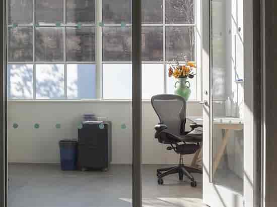 Bright minimalist private office with large windows for meetings and events planning.