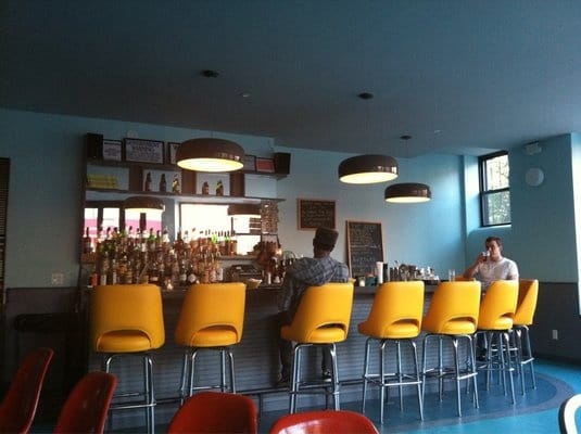 Modern bar with yellow stools at Bearded Lady, ideal for networking events and casual meetups.