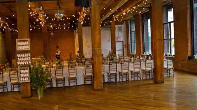 Elegant event space with banquet table, exposed brick, ideal for dinners and gatherings.