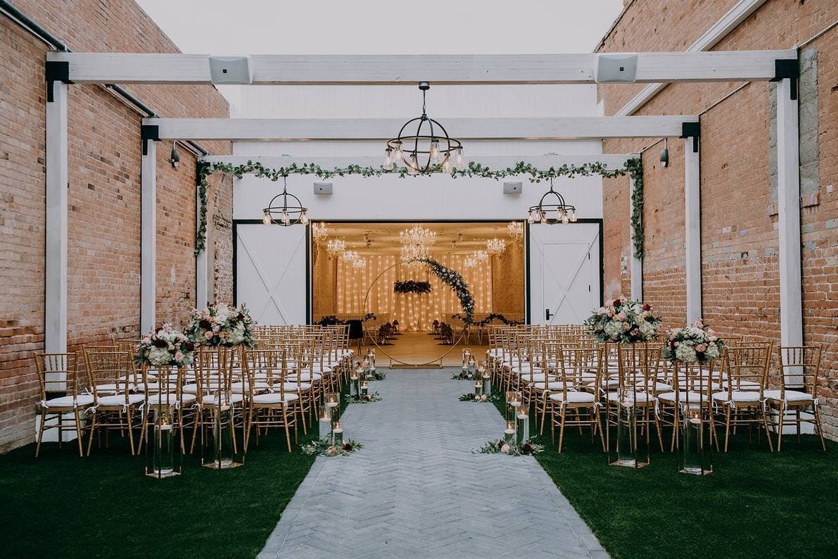 Elegant industrial wedding venue with rustic brick walls and modern chandeliers.