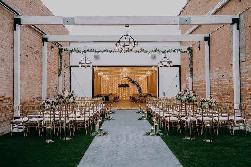 Elegant industrial wedding venue with rustic brick walls and modern chandeliers.