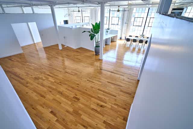 Spacious industrial event space with hardwood floors, ideal for meetings and workshops.