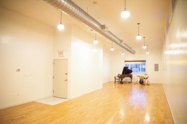 Versatile event space in Greenpoint Hall with natural light and grand piano for gatherings.